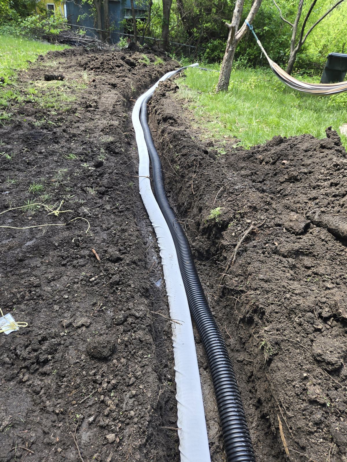 French drain pipe laid in a freshly dug trench