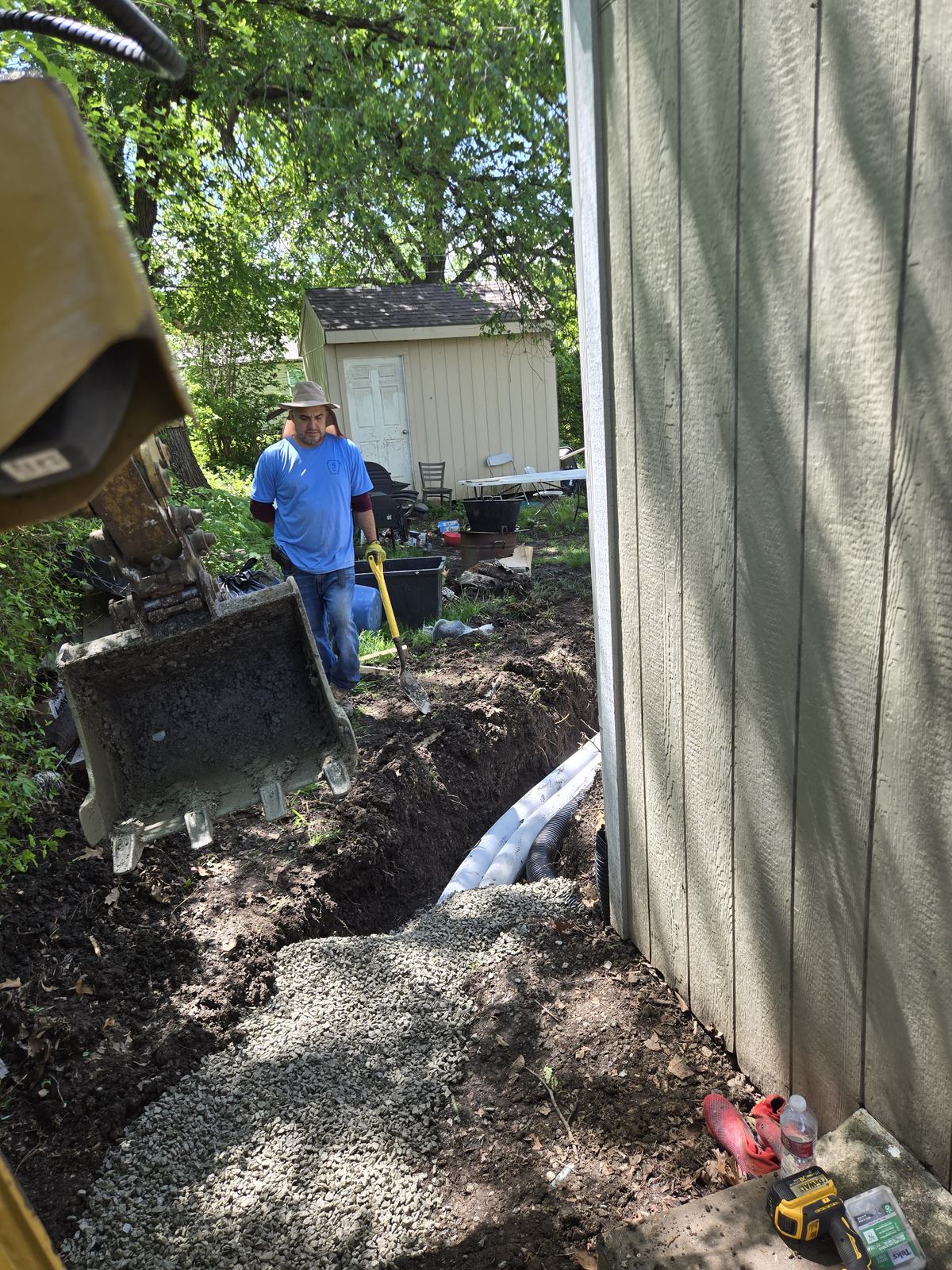 Crew excavating alongside a home with a mini excavator